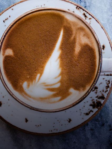 ภาพมุมสูงระยะใกล้ของกาแฟคาปูชิโน่ในถ้วยกาแฟและจานรองสีขาว